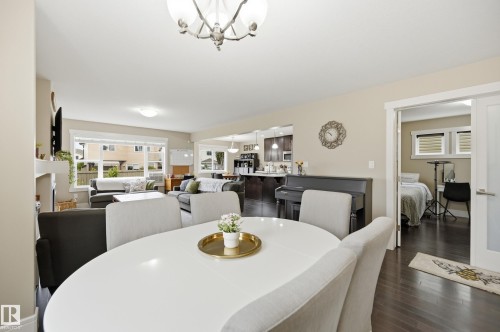 Spacious open-concept living area featuring a fireplace, large windows, wood-finish flooring, and a dining space - 1564 36 Avenue Nw, Edmonton, AB 