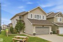 Two-story residence featuring light-colored siding, a dark shingle roof, an attached garage, and multiple windows - 1564 36 Avenue Nw, Edmonton, AB 