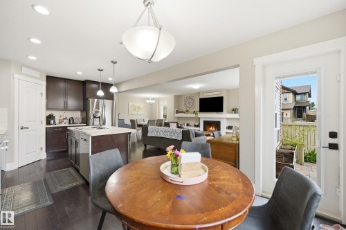 Kitchen featuring dark wood cabinetry, stainless steel appliances, a center island with sink, and dark wood-finish flooring - 1564 36 Avenue Nw, Edmonton, AB 