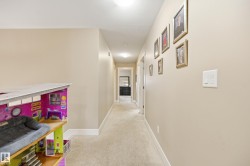 Recessed lighting illuminates the neutral-toned walls, contrasting with white trim and carpeted flooring - 