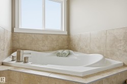 Built-in soaking tub with a stainless steel faucet, set within a tiled surround and illuminated by a large window - 