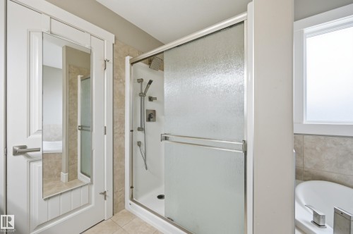 Shower with glass sliding doors, tile surround, and a rain shower head - 1564 36 Avenue Nw, Edmonton, AB 