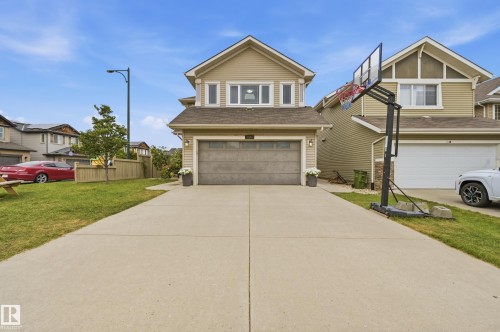 Two-story exterior with horizontal siding, attached garage, concrete driveway, and front lawn - 1564 36 Avenue Nw, Edmonton, AB 