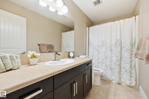 Bathroom featuring a vanity with dark wood-finish cabinetry, a light-toned countertop, and an oval undermount sink - 1564 36 Avenue Nw, Edmonton, AB 