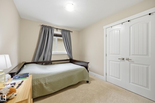 Neutral wall color, window with horizontal blinds, flush mount ceiling light, sliding barn doors with paneling, and neutral carpeting - 1564 36 Avenue Nw, Edmonton, AB 