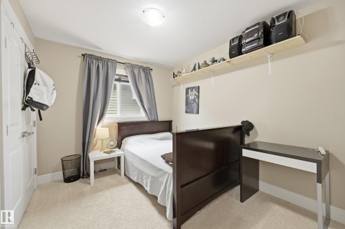 Wall-to-wall carpeting with neutral wall color, window with horizontal blinds, built-in shelving, and a flush-mount ceiling light fixture - 1564 36 Avenue Nw, Edmonton, AB 