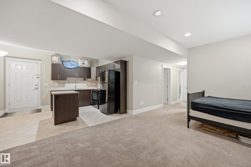 Integrated kitchenette with dark wood-finish cabinetry, light countertops, and built-in appliances - 1564 36 Avenue Nw, Edmonton, AB 