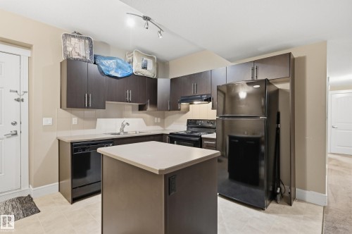 Kitchen featuring dark wood-finish cabinetry, light countertops, an island with integrated power, and tile flooring - 1564 36 Avenue Nw, Edmonton, AB 