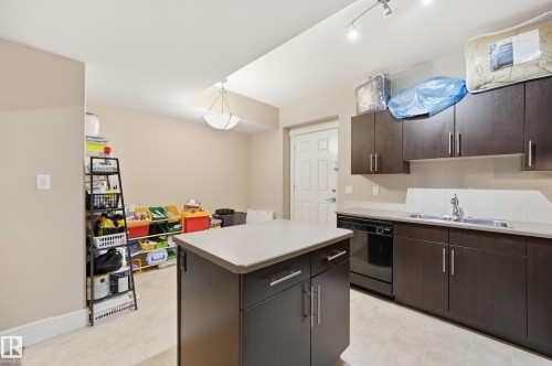 Kitchenette featuring wood-finish cabinetry, light-toned countertops, tile flooring, and track lighting - 1564 36 Avenue Nw, Edmonton, AB 