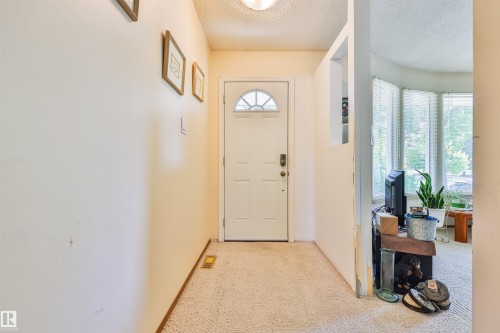 Entryway featuring a white door with an arched window insert, carpet flooring, and a recessed wall cut-out - 9 Hawkins Crescent, Sherwood Park, AB 