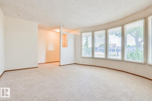 Curved wall with multiple windows, textured carpet flooring, and integrated wall lighting - 9 Hawkins Crescent, Sherwood Park, AB 