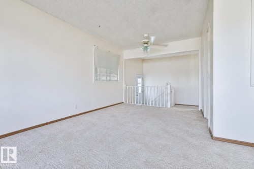 Expansive carpeted area with white walls, a ceiling fan, and a window - 9 Hawkins Crescent, Sherwood Park, AB 