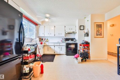 Kitchen featuring white cabinetry, a black refrigerator, a black range with an overhead vent, and a ceiling fan - 9 Hawkins Crescent, Sherwood Park, AB 