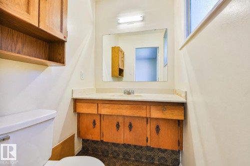 Wood-finish cabinetry, built-in storage, vanity with countertop, wall-mounted mirror, and patterned flooring - 9 Hawkins Crescent, Sherwood Park, AB 