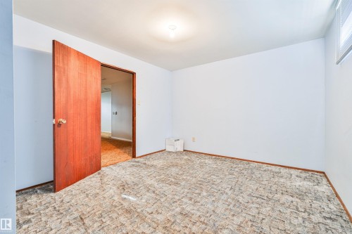 Neutral wall paint, patterned carpet flooring, wood-finish door, and ceiling-mounted light fixture - 9 Hawkins Crescent, Sherwood Park, AB 