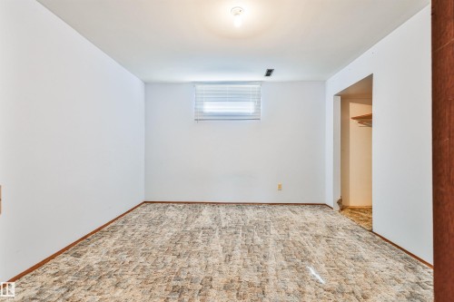Textured carpet flooring, white painted walls, a single window with blinds, and a ceiling-mounted light fixture - 9 Hawkins Crescent, Sherwood Park, AB 