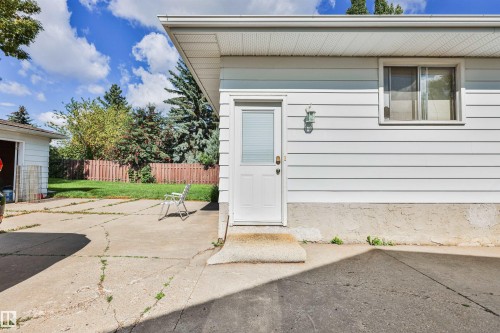 White horizontal siding, window with aluminum frame, exterior door with glass insert, wall-mounted light fixture, and concrete foundation - 9 Hawkins Crescent, Sherwood Park, AB 