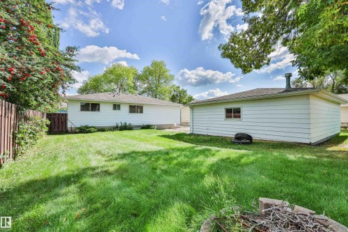 Expansive backyard featuring a lush lawn, mature trees, and a wooden privacy fence - 9 Hawkins Crescent, Sherwood Park, AB 