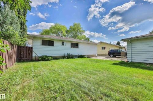 Expansive grassy yard with a wood fence, mature perimeter trees, and a detached structure - 9 Hawkins Crescent, Sherwood Park, AB 