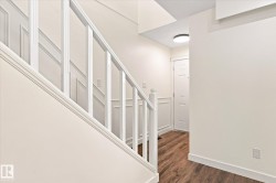 White painted staircase with wood-finish flooring, wainscoting, and a flush-mount ceiling light fixture - 