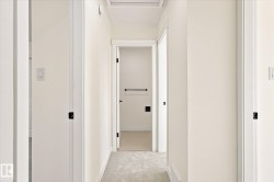 Hallway with neutral wall tones and light-colored carpeting - 