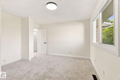 Light gray wall-to-wall carpeting, white interior walls, white window trim, white interior door, and a flush mount ceiling light fixture - 17325 85 Avenue Nw, Edmonton, AB 