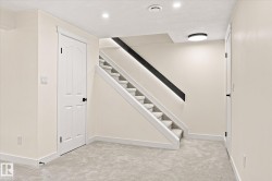 Staircase featuring carpeted treads and a modern black handrail with integrated lighting - 