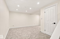 Recessed ceiling lighting, light gray carpet, white interior door with black hardware, and light-toned walls - 