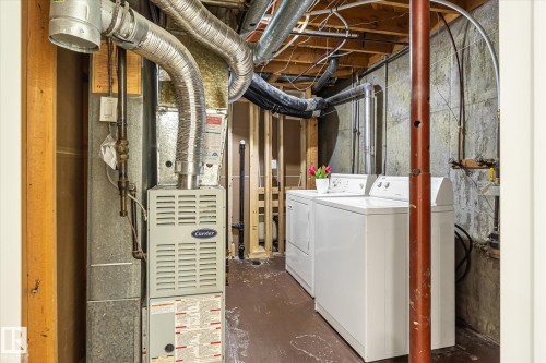 Laundry area featuring a side-by-side washer and dryer, exposed ceiling joists, ductwork, and concrete walls - 17325 85 Avenue Nw, Edmonton, AB 