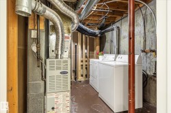 Laundry area featuring a side-by-side washer and dryer, exposed ceiling joists, ductwork, and concrete walls - 