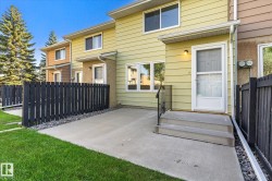 Concrete patio with a black picket fence and manicured lawn - 