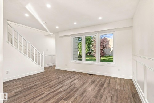 Wood-finish flooring throughout, bright white walls, recessed ceiling lighting, triple-pane windows, and wainscoting detail - 17325 85 Avenue Nw, Edmonton, AB 