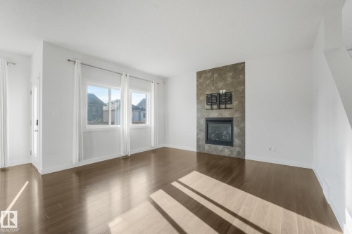 Wood-finish flooring, white walls, and a stone-clad fireplace - 7832 Erasmus Wynd Nw, Edmonton, AB 