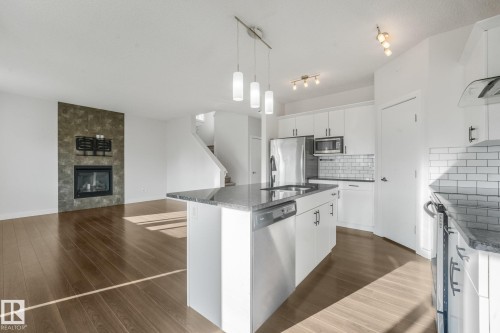 Open-concept kitchen with a central island, recessed sink, stainless steel appliances, and white subway tile backsplash - 7832 Erasmus Wynd Nw, Edmonton, AB 