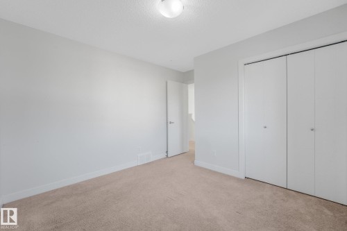 Neutral tone wall paint, carpet flooring, baseboards, and bi-fold closet doors - 7832 Erasmus Wynd Nw, Edmonton, AB 