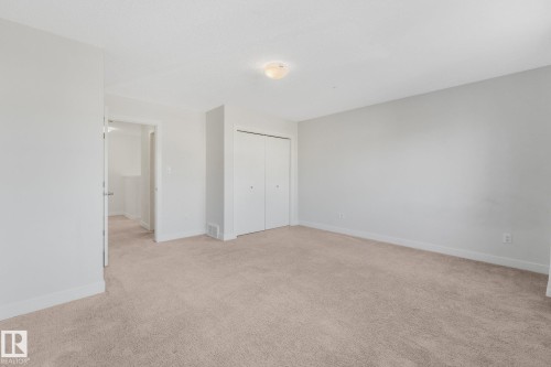 Light-toned wall finishes, neutral carpet, and a flush mount ceiling light fixture - 7832 Erasmus Wynd Nw, Edmonton, AB 