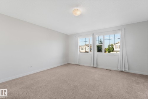 Carpeted flooring, neutral wall color, two windows, ceiling-mounted light fixture, white trim - 7832 Erasmus Wynd Nw, Edmonton, AB 
