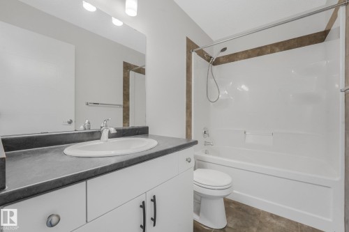 White vanity with dark countertop, large mirror, and three-light fixture - 7832 Erasmus Wynd Nw, Edmonton, AB 