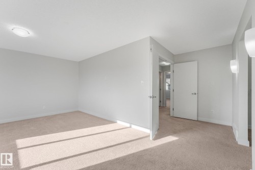 Neutral color palette with light gray walls, light beige carpet, and white trim - 7832 Erasmus Wynd Nw, Edmonton, AB 