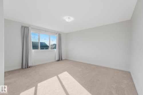 Neutral tone wall finishes, ceiling-mounted light fixture, and broad window - 7832 Erasmus Wynd Nw, Edmonton, AB 