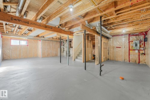 Unfinished basement featuring exposed wood beams, a window, and utility access - 7832 Erasmus Wynd Nw, Edmonton, AB 