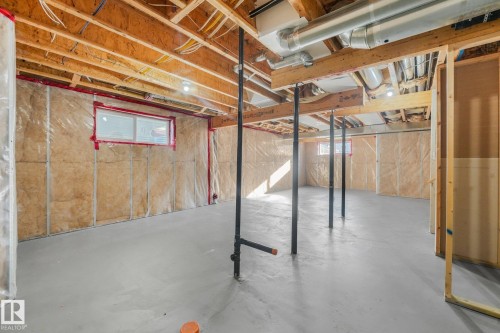Unfinished lower level featuring concrete flooring, exposed wood joists, a horizontal window, and visible HVAC ductwork - 7832 Erasmus Wynd Nw, Edmonton, AB 