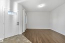 White panel front door with transom window, tile entry, wood-finish flooring, white walls, and a flush mount ceiling light - 7832 Erasmus Wynd Nw, Edmonton, AB 