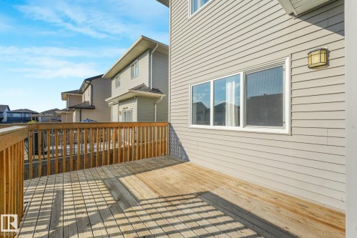 Expansive wood deck with a full wood railing, siding exterior, multi-pane windows, and an exterior wall light fixture - 7832 Erasmus Wynd Nw, Edmonton, AB 