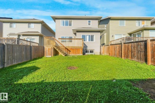 Expansive backyard featuring a manicured lawn, wood fencing, and a multi-level wood deck with stairs - 7832 Erasmus Wynd Nw, Edmonton, AB 