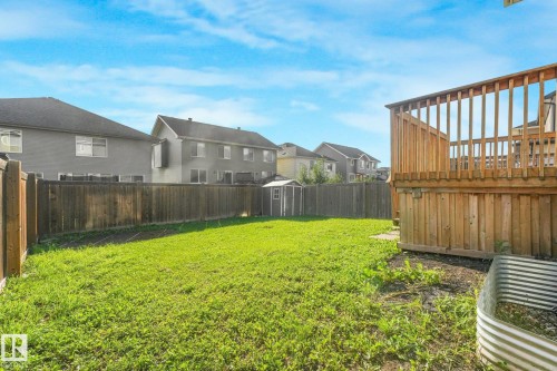 Spacious backyard featuring a wooden privacy fence, a storage shed, and a raised wooden deck - 7832 Erasmus Wynd Nw, Edmonton, AB 