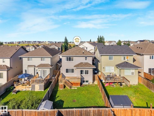 Rear exterior featuring a multi-level deck, ground-level patio, and a sloped lawn - 7832 Erasmus Wynd Nw, Edmonton, AB 