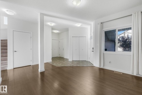 Wood-finish flooring, recessed lighting, and a large window with privacy drapes - 7832 Erasmus Wynd Nw, Edmonton, AB 