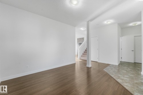 Wood-finish flooring, recessed lighting, white walls, and a staircase with carpeted treads - 7832 Erasmus Wynd Nw, Edmonton, AB 