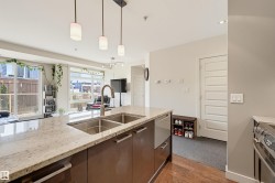 Kitchen island featuring a dual stainless steel undermount sink, gooseneck faucet, and light-toned granite countertop - 